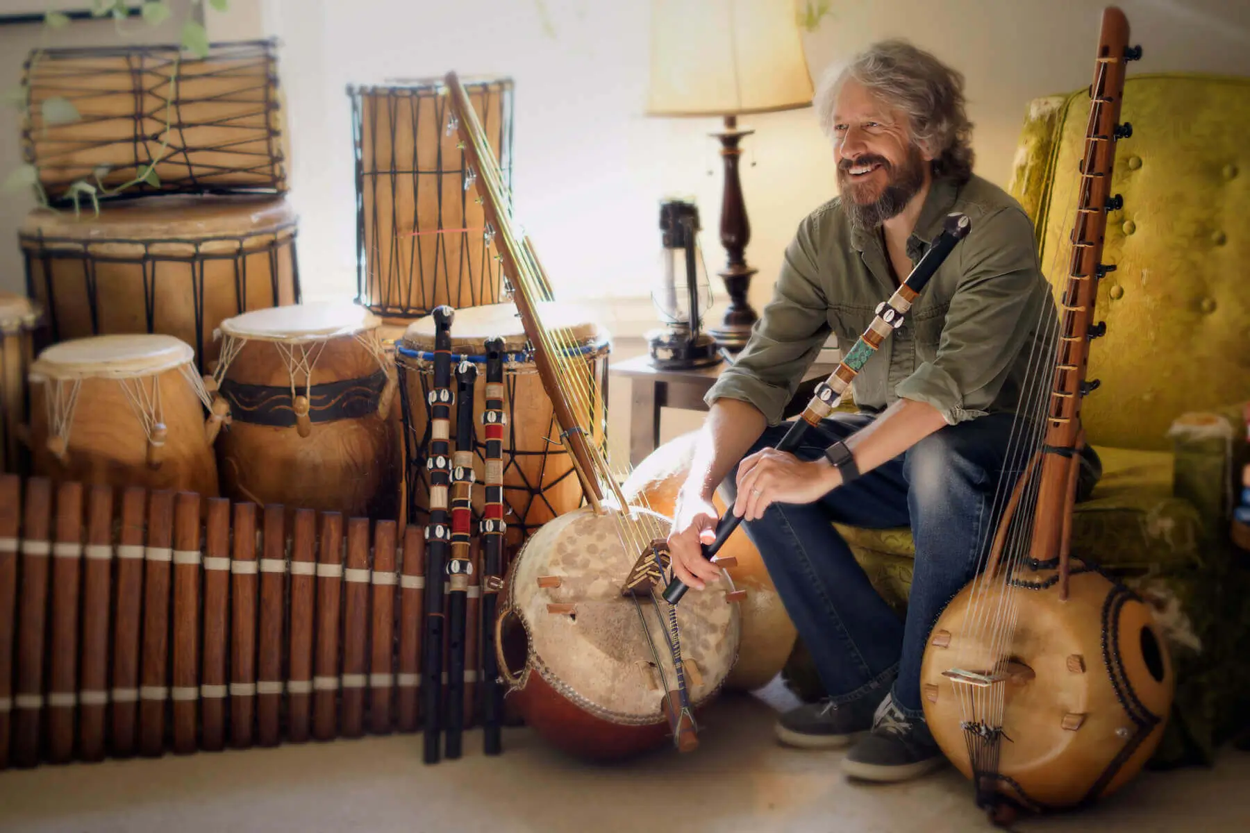 Dave Kobrenski holding a Fula flute among West African drums and string instruments
